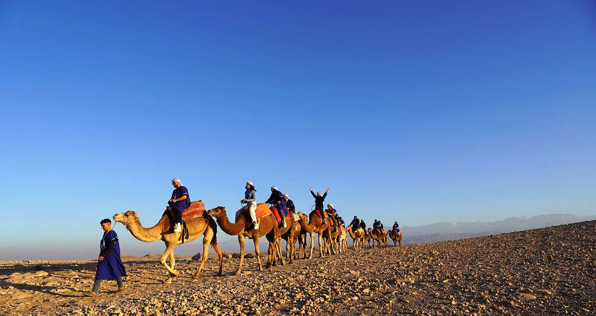 People riding camels in the Agafay Desert, Morocco