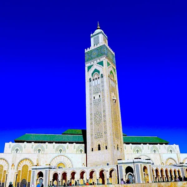 Vibrant photo of Hassan II Mosque in Casablanca, featured on a Morocco Tours & Transfers journey, highlighting its grand architecture and oceanfront backdrop