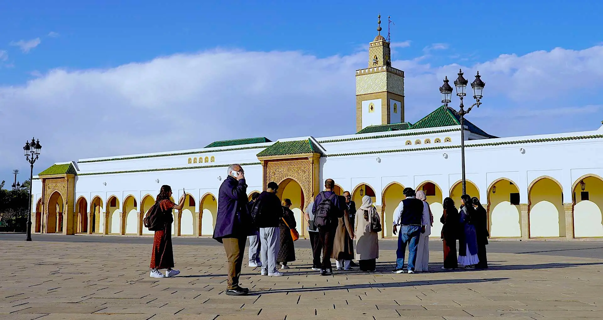 Guide with a group of tourists in front of a mosque near the Royal Palace in Rabat, Morocco