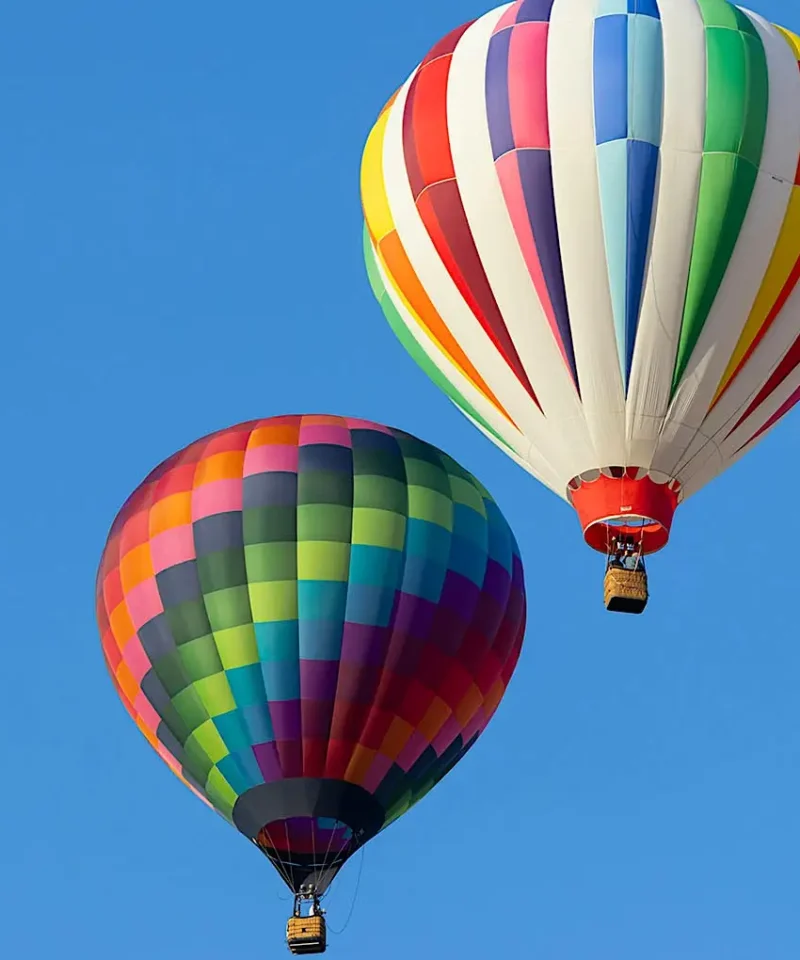 Hot air balloon flying above Marrakech with tourists onboard, offering a stunning view of the cityscape and snow-capped Atlas Mountains
