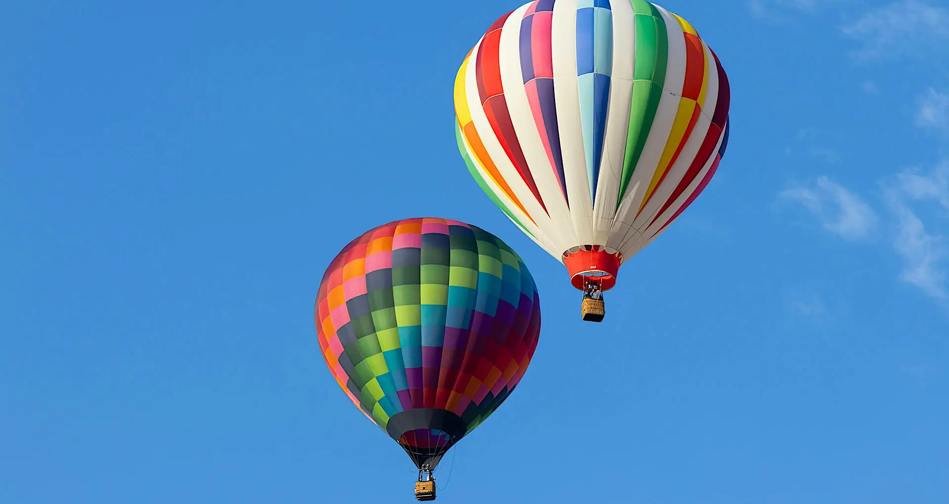 Hot air balloon flying above Marrakech with tourists onboard, offering a stunning view of the cityscape and snow-capped Atlas Mountains