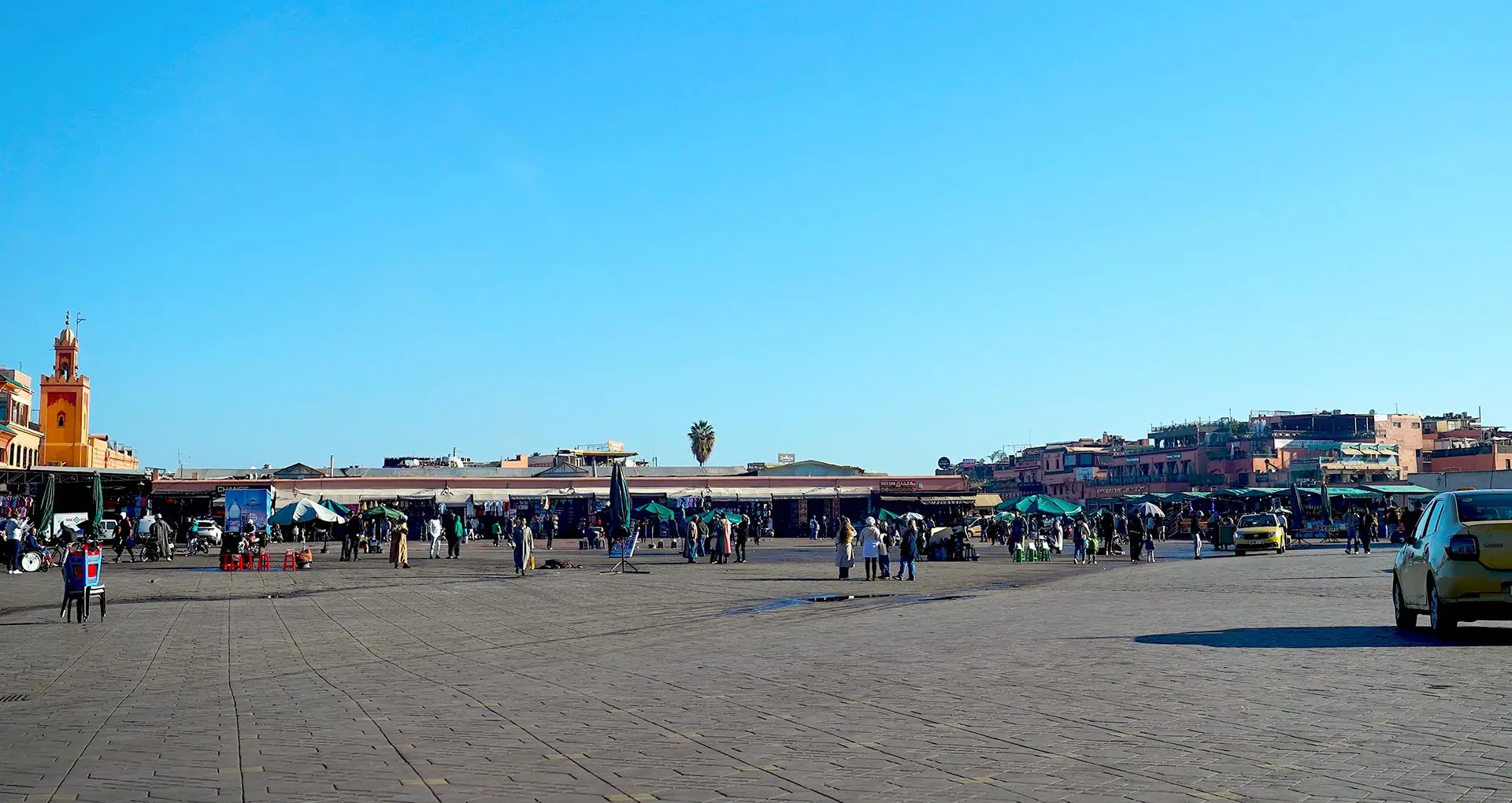 A morning scene at Jemaa el-Fnaa Square in Marrakech at 10 AM, featuring snake charmers performing, monkeys present in the square, and juice vendors organizing their stalls for the day